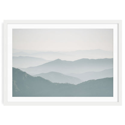 Minimalist foggy mountain landscape in soft neutral blue and gray tones, showing gentle overlapping ridges and atmospheric mist modern calming wall art print.
