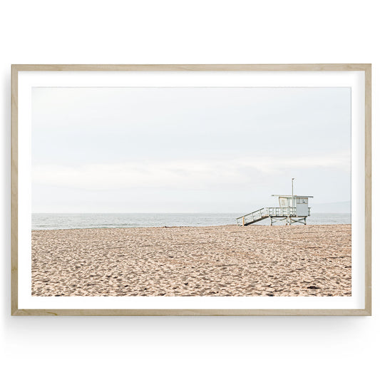 Muted coastal photograph of a lifeguard tower on Manhattan Beach, California, with soft tones and a serene ocean backdrop, framed as wall art.