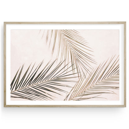 Minimalist tropical palm leaves wall art in pale pink tones, horizontal fine art print for bedroom or living room, nature-inspired neutral home decor.
